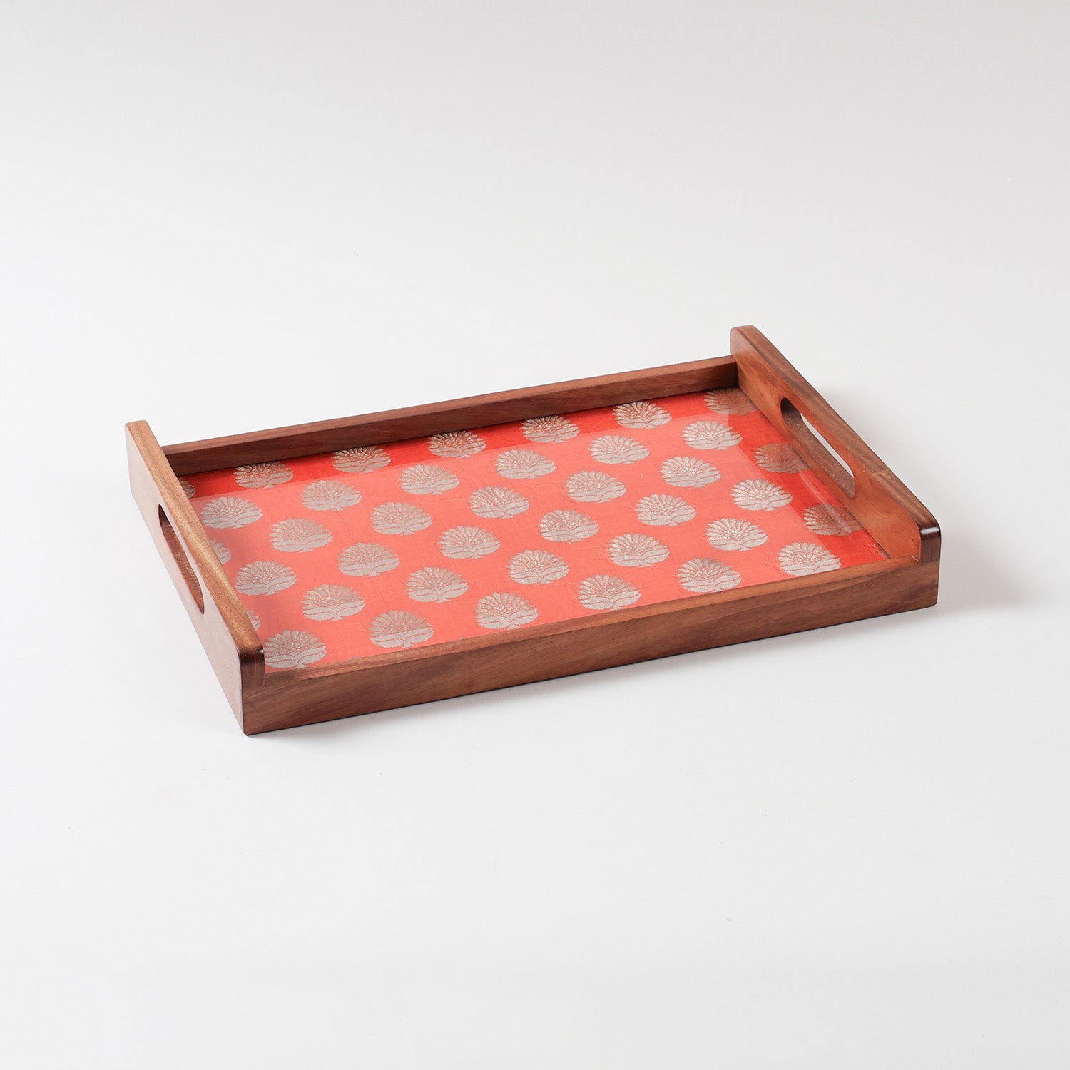 Angled view of handcrafted wooden tray showing orange chanderi fabric with golden paisley pattern beneath glass top