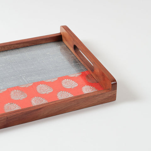 Angled close-up of orange and grey chanderi fabric with golden paisley motifs used in a handcrafted wooden serving tray