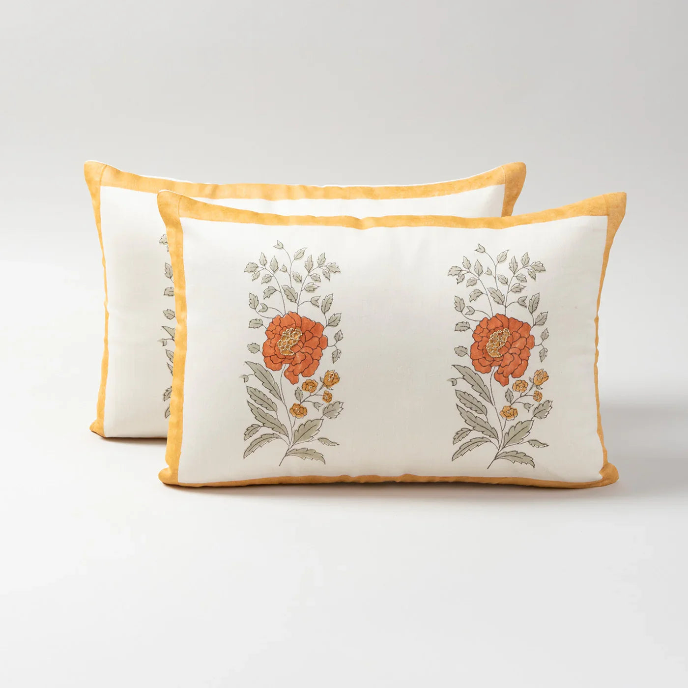 Set of 2 Chanderi lumbar cushion covers featuring orange marigold buta block prints and hand embroidery on an off-white base