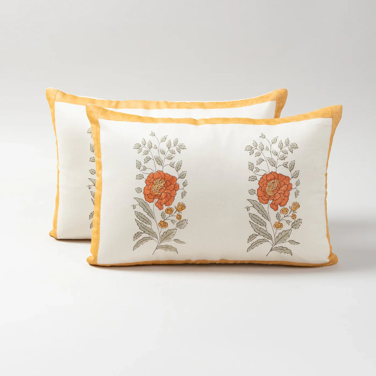 Set of 2 Chanderi lumbar cushion covers featuring orange marigold buta block prints and hand embroidery on an off-white base