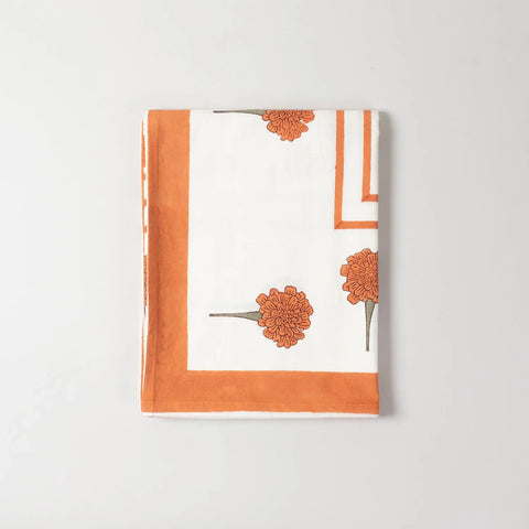 Detailed corner view of an orange marigold buti block printed table cover highlighted with solid orange border