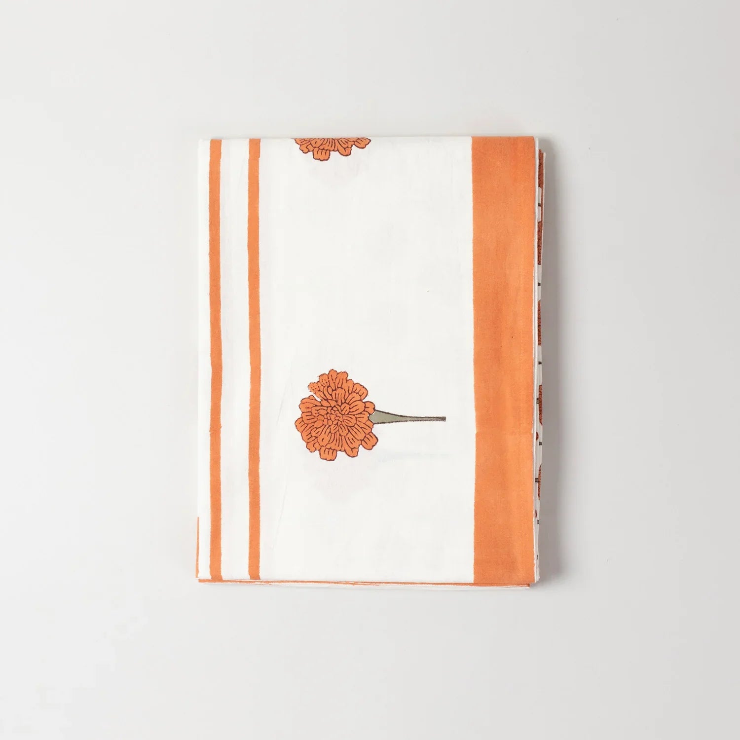 Folded cotton table cloth showcasing orange marigold buti block printed motifs and handcrafted detailing