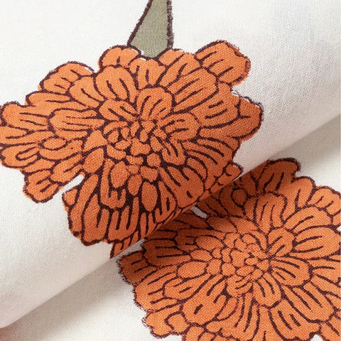 Close-up of orange marigold buti floral block print motifs on a handcrafted cotton table cloth