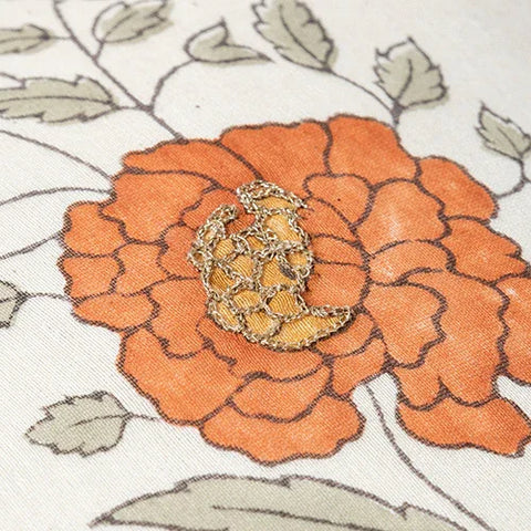 Close-up of orange marigold, buta block print and hand embroidery on a Chanderi lumbar cushion cover