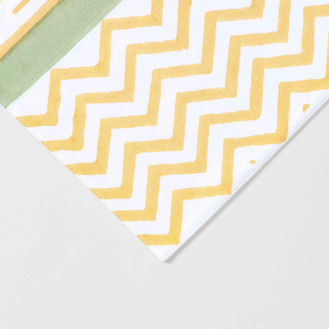 Close-up of orange line motifs green side panels and yellow zigzag border on cotton table runne
