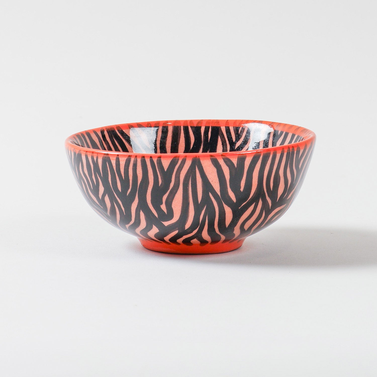 Handmade African ceramic bowl featuring a striking black zebra stripe pattern on an orange base, suitable as a snack bowl, salad bowl, or decorative tableware piece