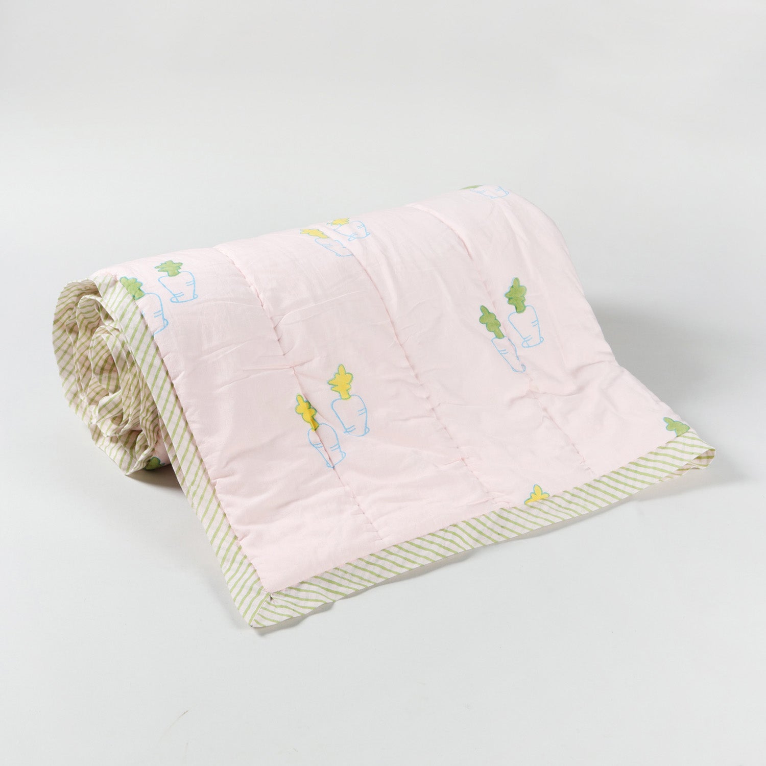 Rolled reversible cotton quilt featuring bunny and carrot motifs, highlighting the quilted layers and lightweight construction