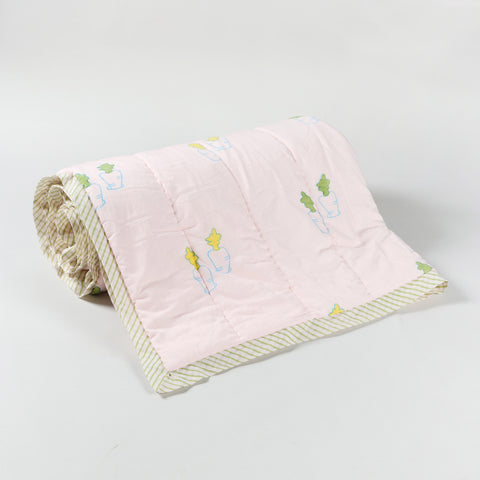 Rolled reversible cotton quilt featuring bunny and carrot motifs, highlighting the quilted layers and lightweight construction