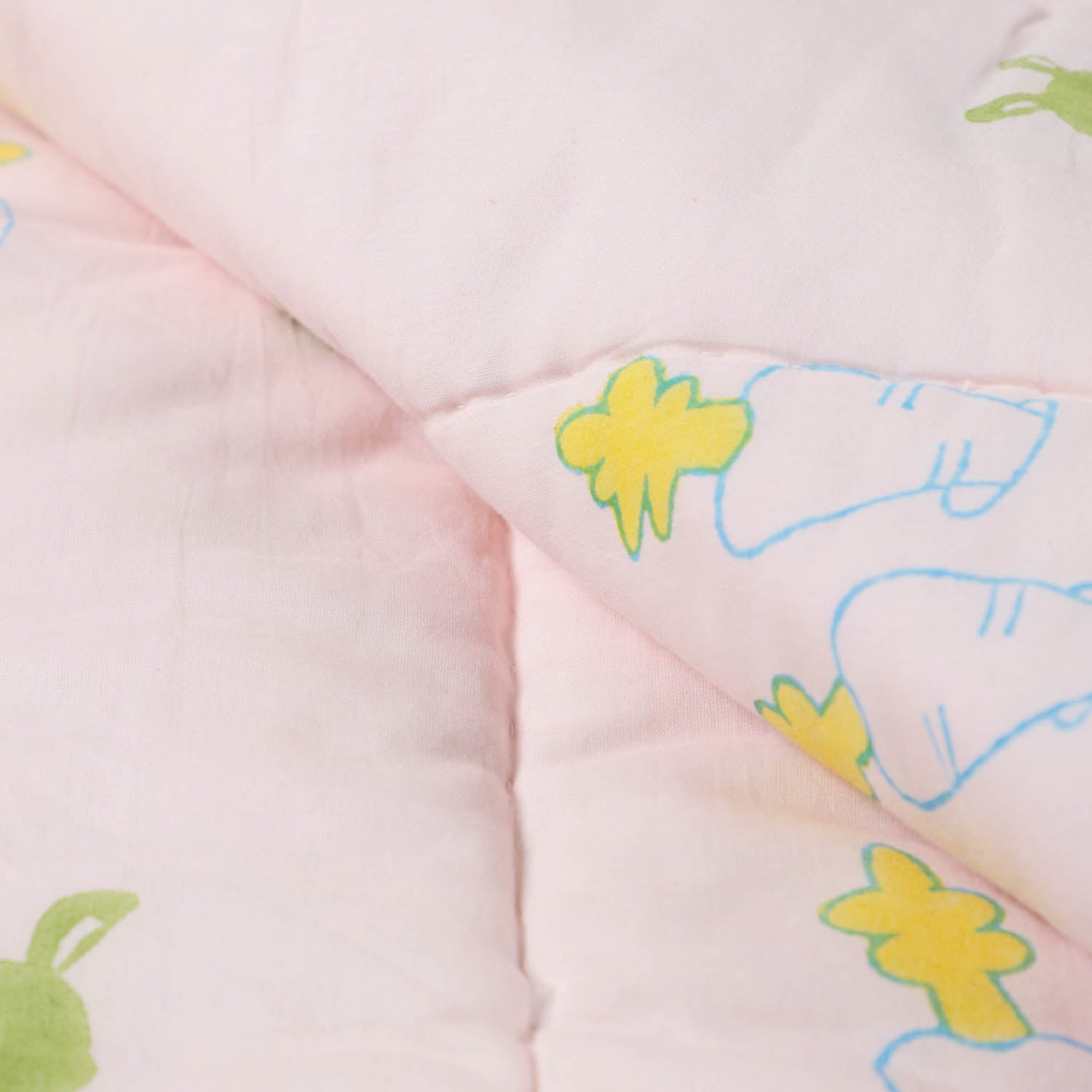 Detailed close-up of bunny and carrot block printed cotton quilt fabric showing stitching, breathable cotton, and pastel colour palette