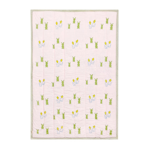 Full view of a 60x40 reversible cotton quilt with pastel bunny and carrot motifs on a light pink base