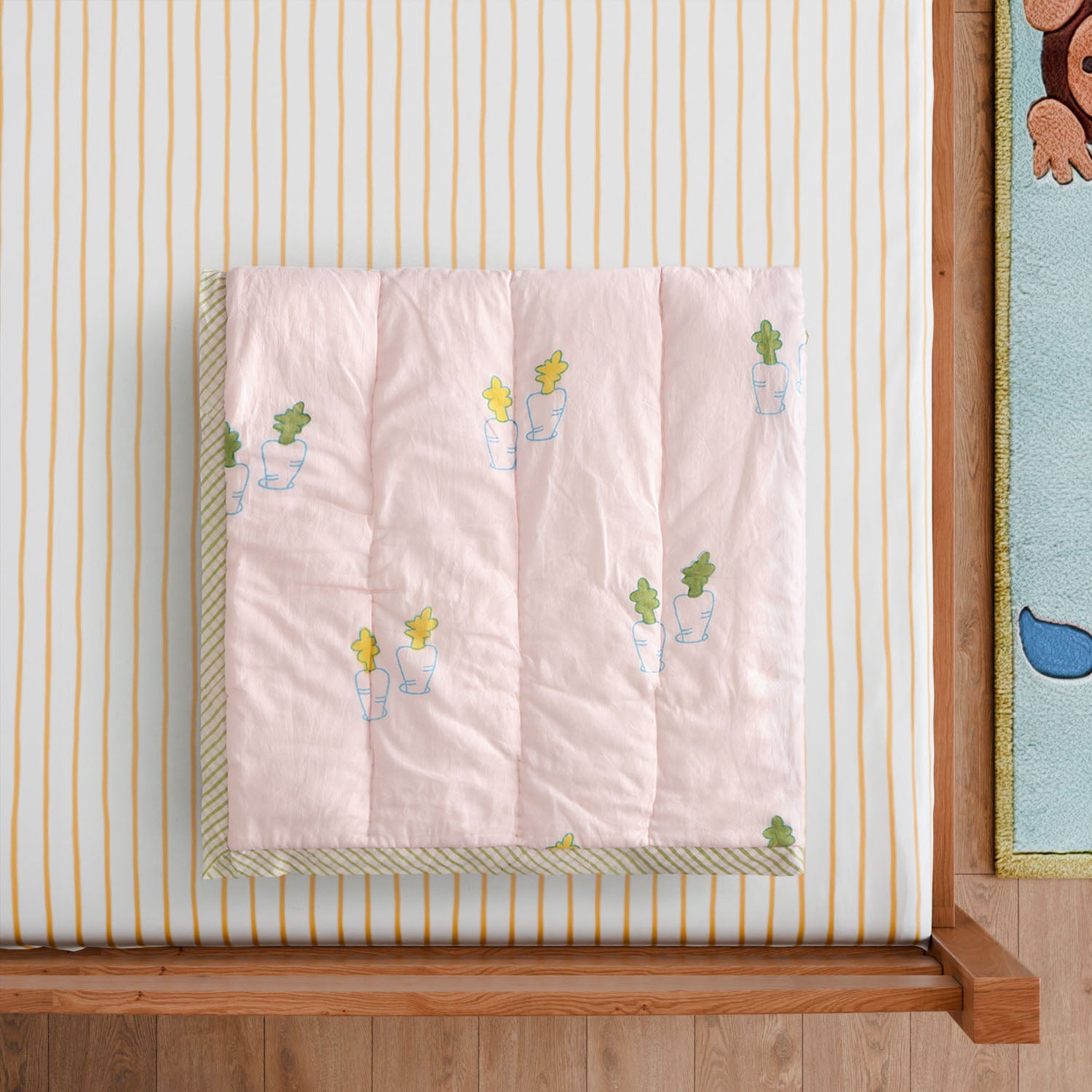 Styled close-up of a hand block printed cotton quilt featuring pastel bunny and carrot motifs, showcasing artisan craftsmanship and soft texture