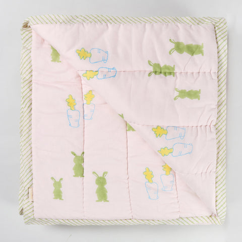 Reversible cotton quilt displaying both front and back designs with playful bunny and carrot block printed motifs