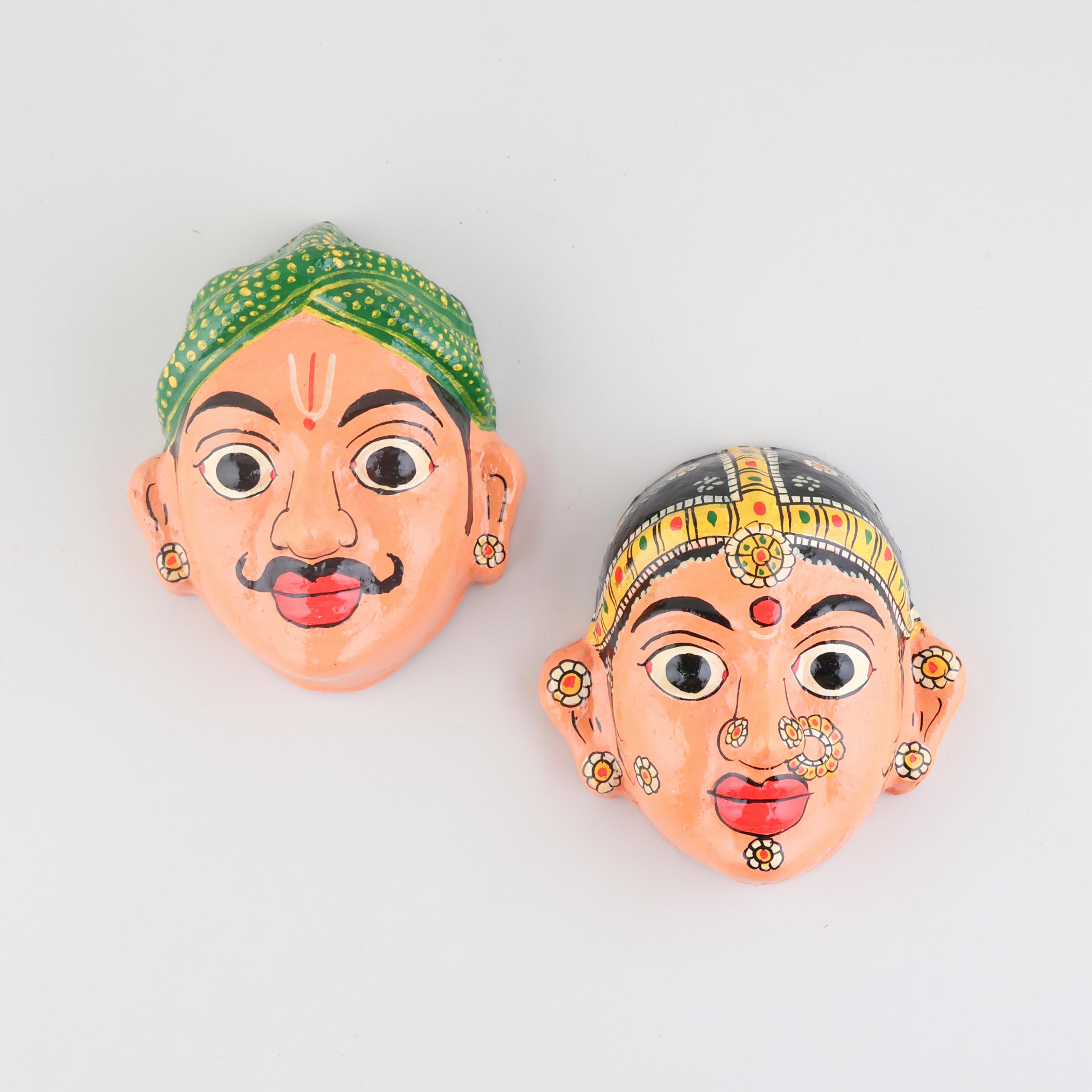 Hand-painted peach Cheriyal couple mask set crafted from papier-mache, featuring traditional Telangana folk art motifs and detailed handcrafted decoration on a plain background