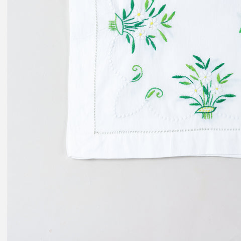 Detailed corner view of a handcrafted table runner featuring elegant periwinkle-inspired floral embroidery along the border