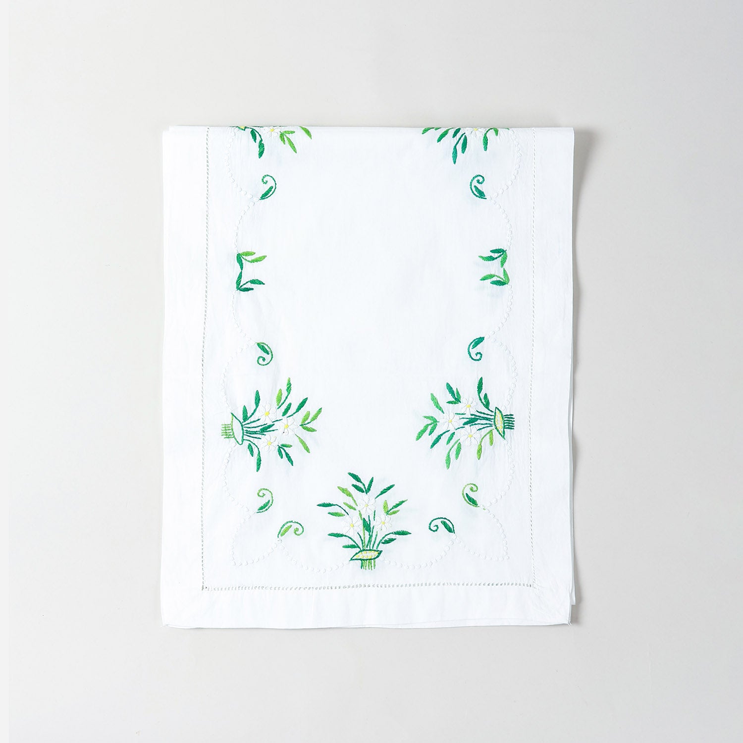 Folded white cotton table runner showcasing delicate periwinkle-inspired floral embroidery and handcrafted Bengal chikankari detailing