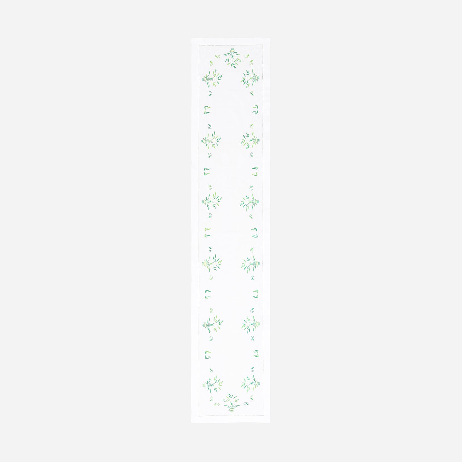 Full-length embroidered table runner featuring white and green floral motifs inspired by periwinkle blooms on a white cotton base, displayed on a plain background 