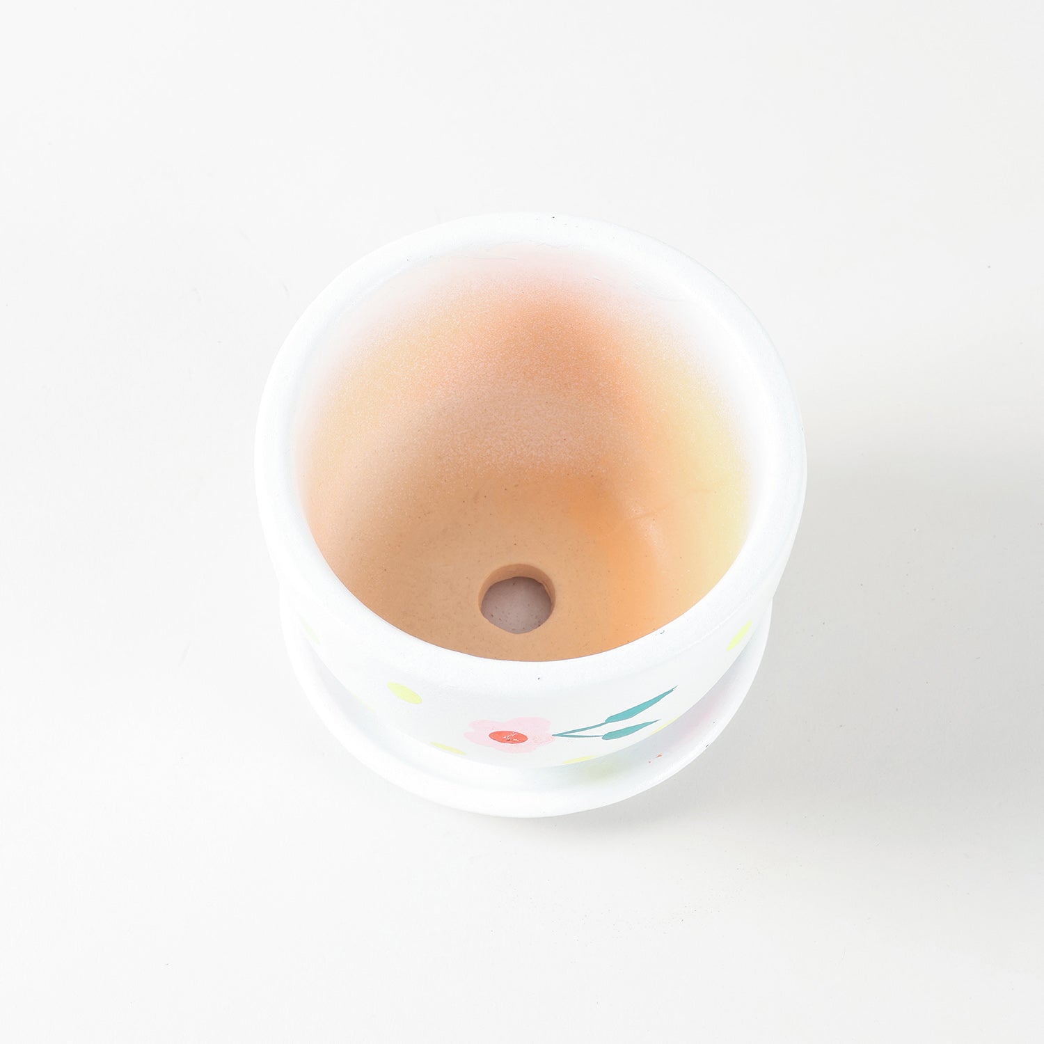 White ceramic flower pot with pink blossom design and matching drainage tray.
