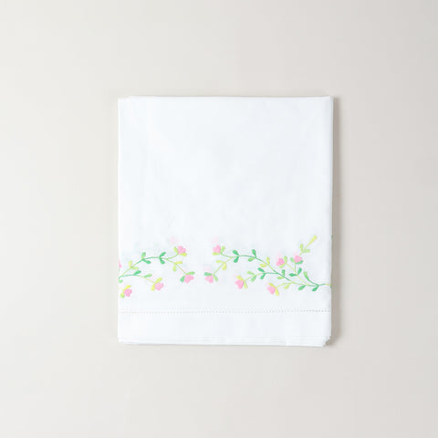 Folded embroidered cotton table cloth showcasing pink floral motifs and intricate cutwork craftsmanship