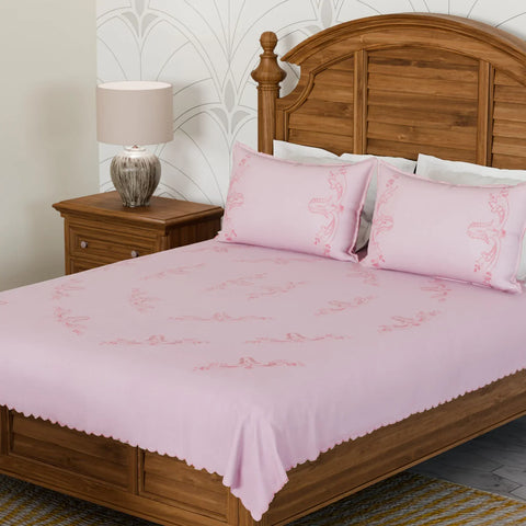 Pink cotton king size bedcover with dark pink chikankari hand embroidery and matching pillow cases styled in an elegant bedroom