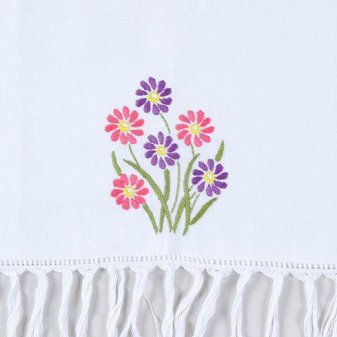 Close-up of pink and purple daisy hand embroidery with textured tassel fringe on cotton kitchen towel
