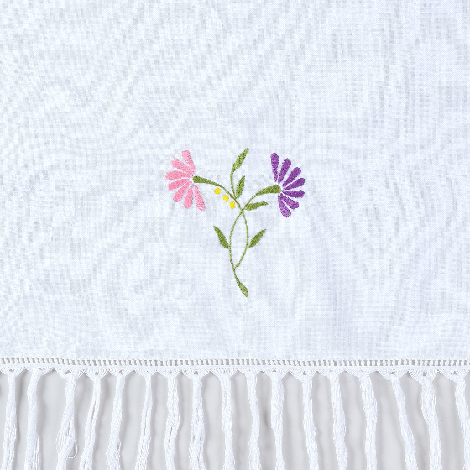 Close-up of pink and purple floral hand embroidery with tasselled edge detail on cotton kitchen towel