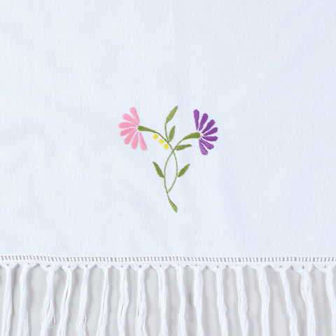 Close-up of pink and purple floral hand embroidery with tasselled edge detail on cotton kitchen towel