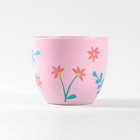 Ceramic planter at eye level with soft pink floral detailing and tapered cylinder shape.
