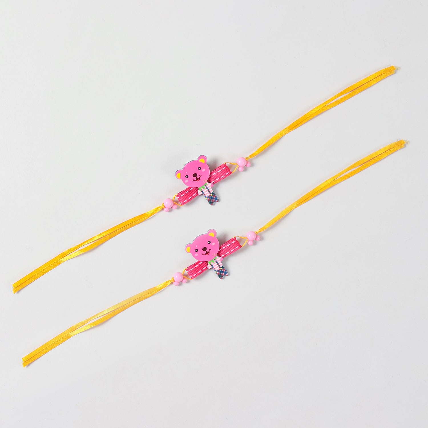 Full-length view of the pink Teddy Bear Wooden Kids Rakhi Set of 2 showing the complete yellow ribbon band and handcrafted wooden teddy design.