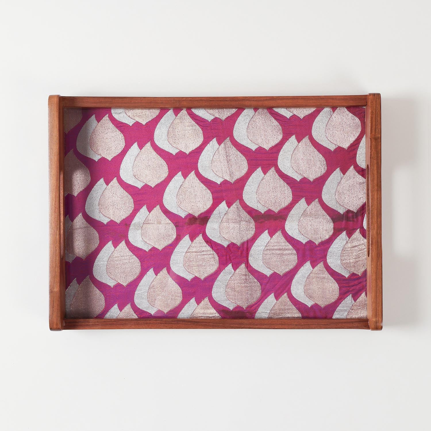 Top-view of glass-topped wooden tray highlighting glossy finish and golden paisley fabric underneath