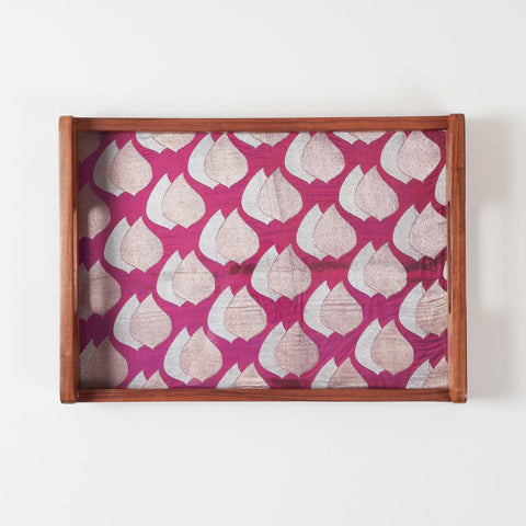 Top-view of glass-topped wooden tray highlighting glossy finish and golden paisley fabric underneath