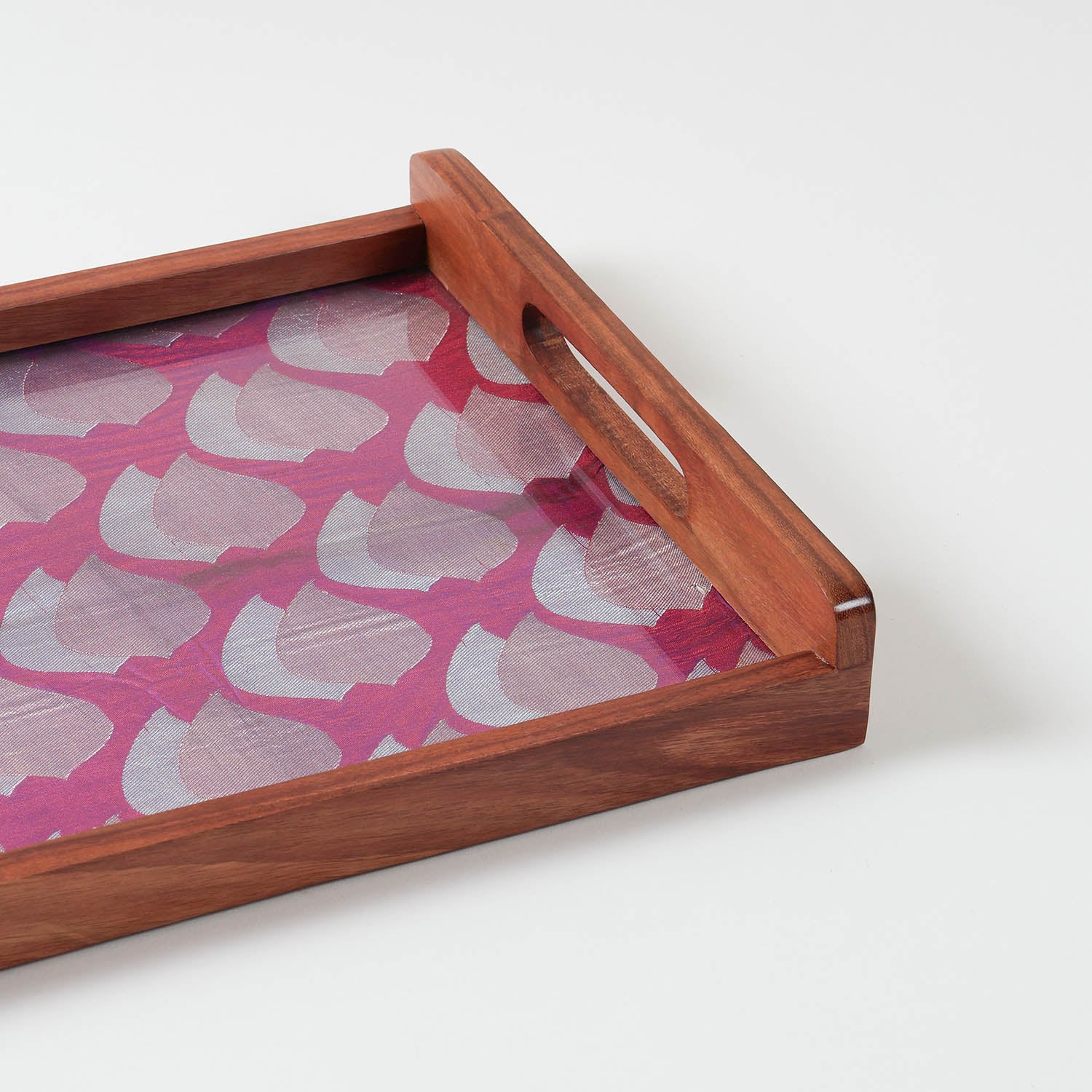 Corner angled view of handcrafted wooden tray showing purple fabric base with golden paisley pattern under glass top