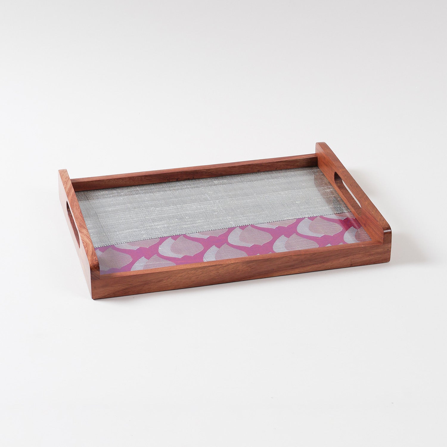 Angled view of a handcrafted wooden tray showing purple and grey fabric panels with golden paisley motifs beneath a glass top