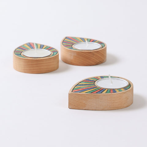 Side view of three handcarved rainbow raindrop wooden t-light holders showcasing layered contours and colourful detailing