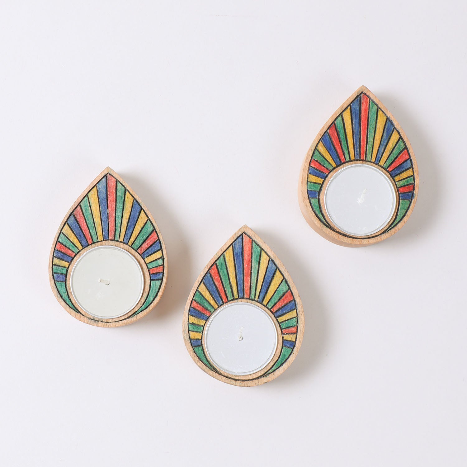 Top view of a set of three hand carved wooden t-light holders featuring rainbow raindrop designs and candle recesses