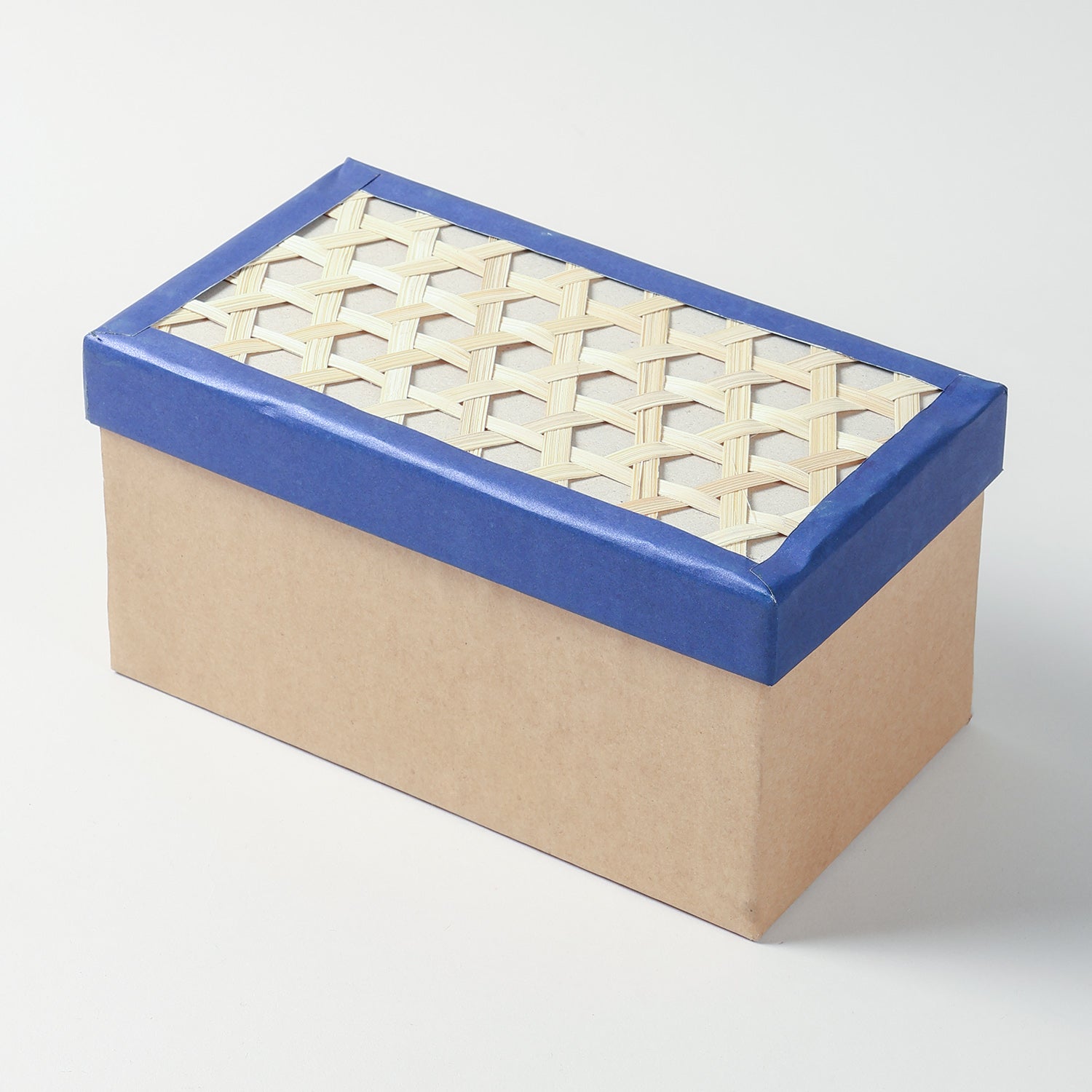 Close-up of the woven bamboo lid and blue fabric border on the elongated rectangular cardboard storage box 