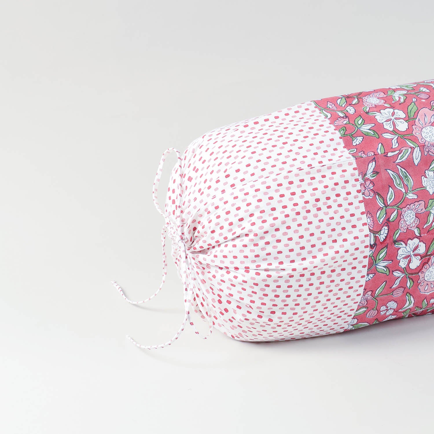 Close-up view of a hand block-printed pattern on a drawstring  red cotton bolster cover, highlighting artisan craftsmanship