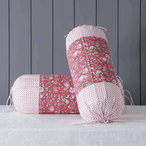 Red hand block printed bolster cover set styled on a bed adding warmth, colour and handcrafted charm to home decor