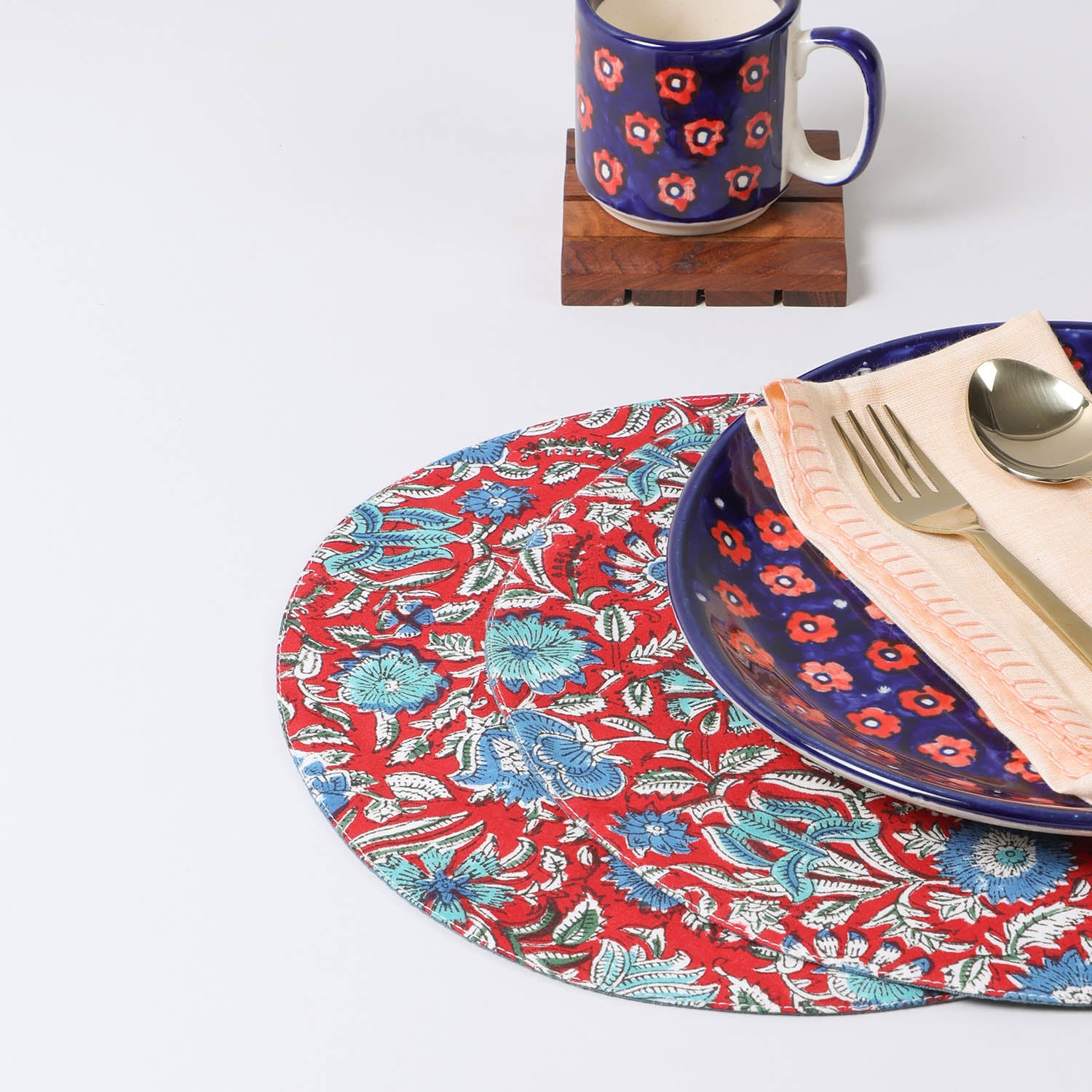 Set of two round cotton placemats with red and blue block printed patterns styled on a dining table, creating a vibrant table setting and dining table décor