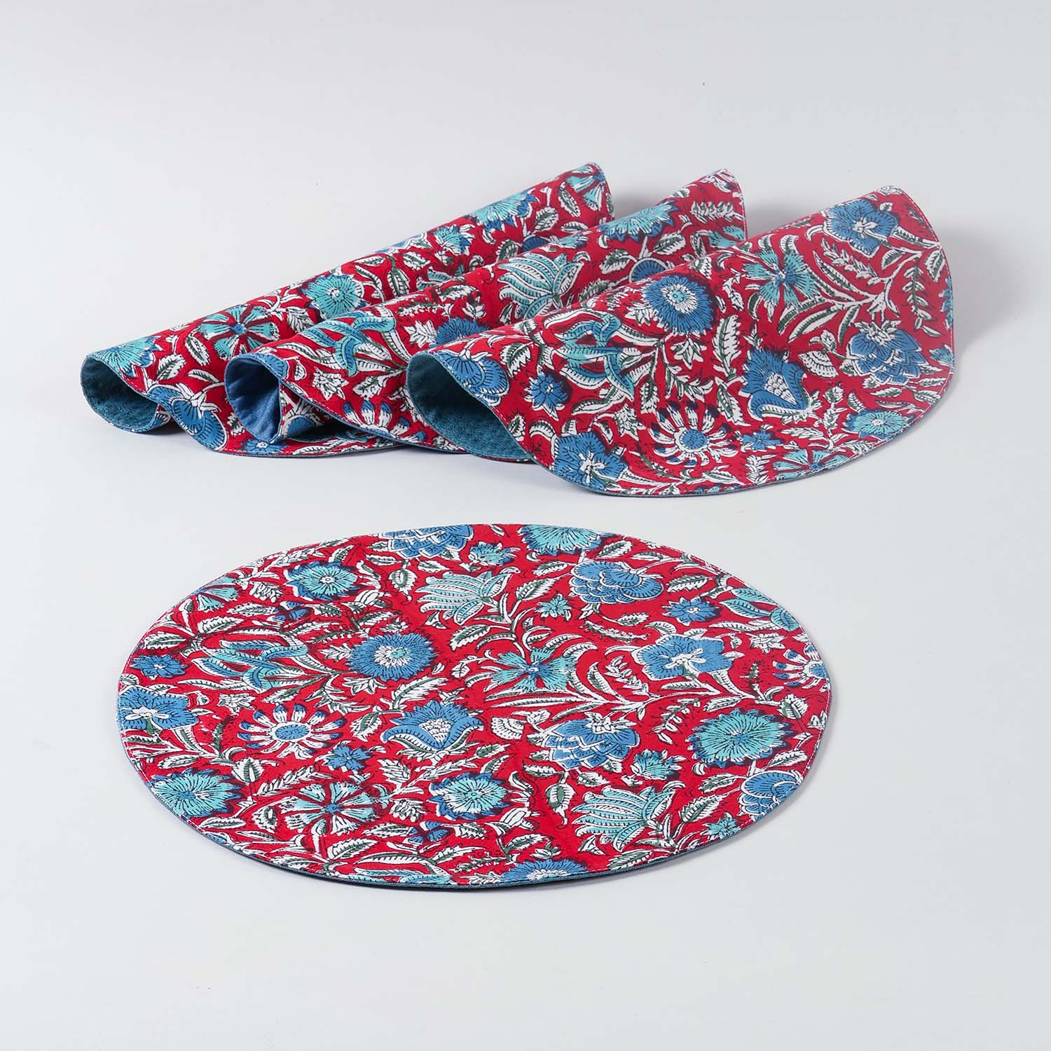 Set of four round cotton placemats featuring red and blue block printed patterns arranged on a plain background, ideal for dining table settings and table décor
