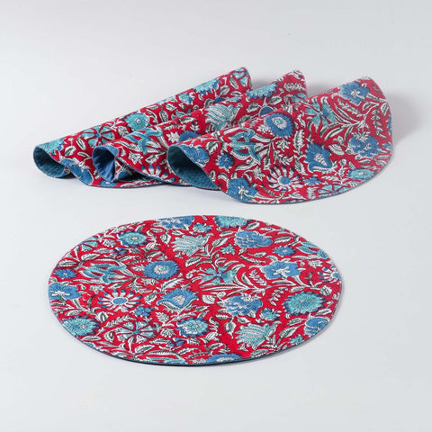 Set of four round cotton placemats featuring red and blue block printed patterns arranged on a plain background, ideal for dining table settings and table décor