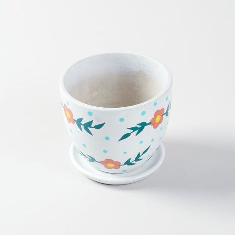 Ceramic planter with a drainage plate shown in high-angle view, highlighting red floral detailing on a white base
