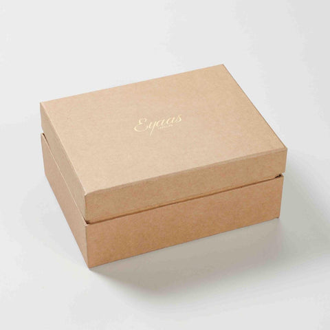 Angled view of a closed gift box containing a set of two red ceramic mugs with blue floral hand-painted artwork