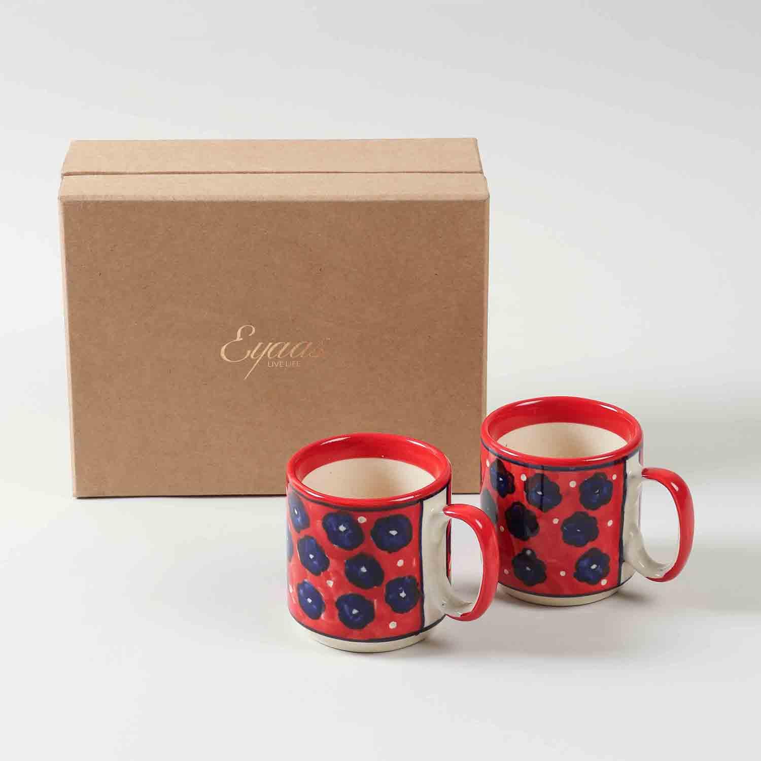 Red ceramic mug gift pack of two with blue floral hand-painted design presented in a cardboard gift box