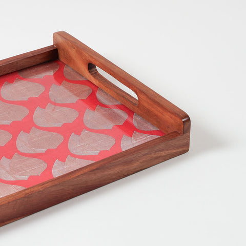 Corner angled close-up view of a handcrafted rectangular wooden tray with red handwoven fabric  featuring paisley motifs in golden
