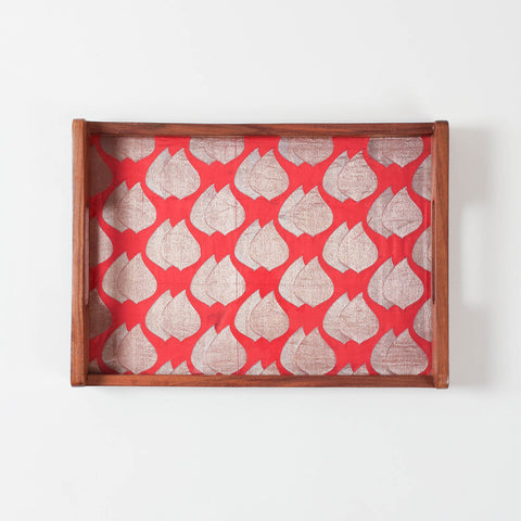 Close-up of a glass-topped wooden tray, highlighting glossy finish and decorative paisley fabric beneath