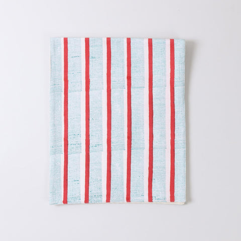 Folded cotton table runner featuring red and green stripe block printed patterns highlighting soft fabric and handcrafted detailing