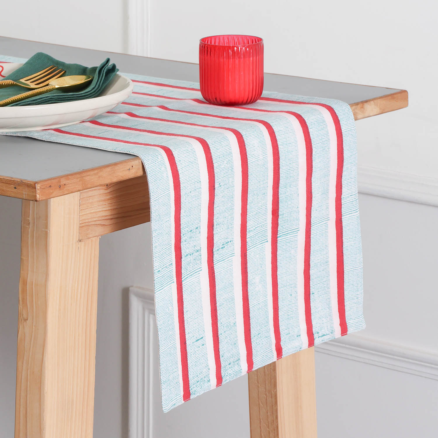 Red and green stripe block printed cotton table runner styled on a dining table, creating a vibrant table setting and dining table décor for everyday and festive meals