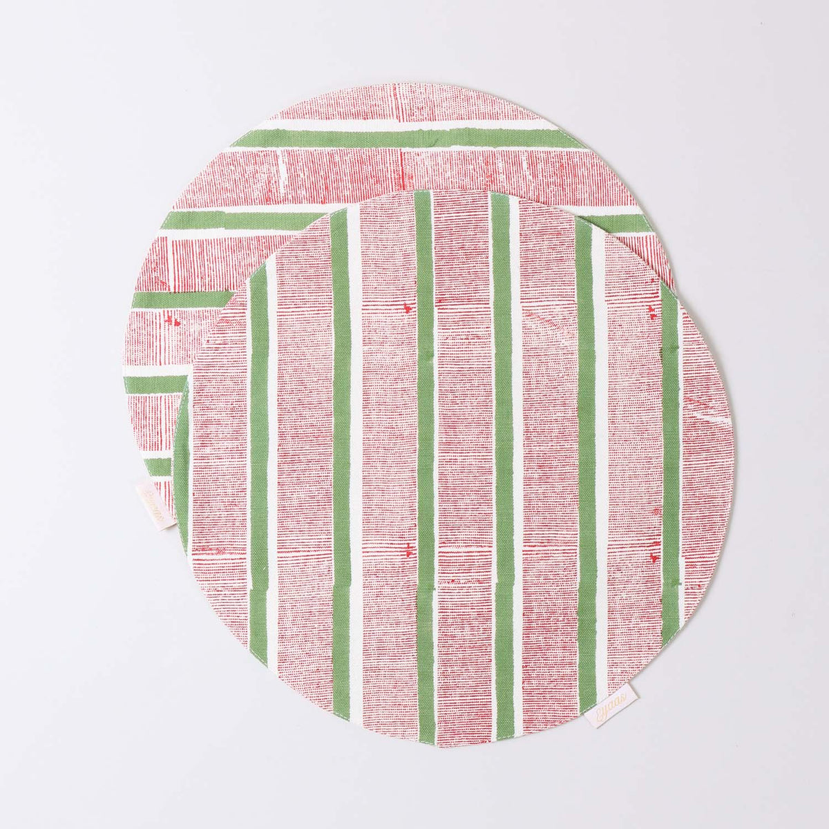 Set of 2 round cotton placemats featuring red and green stripe block printed designs displayed on a plain background
