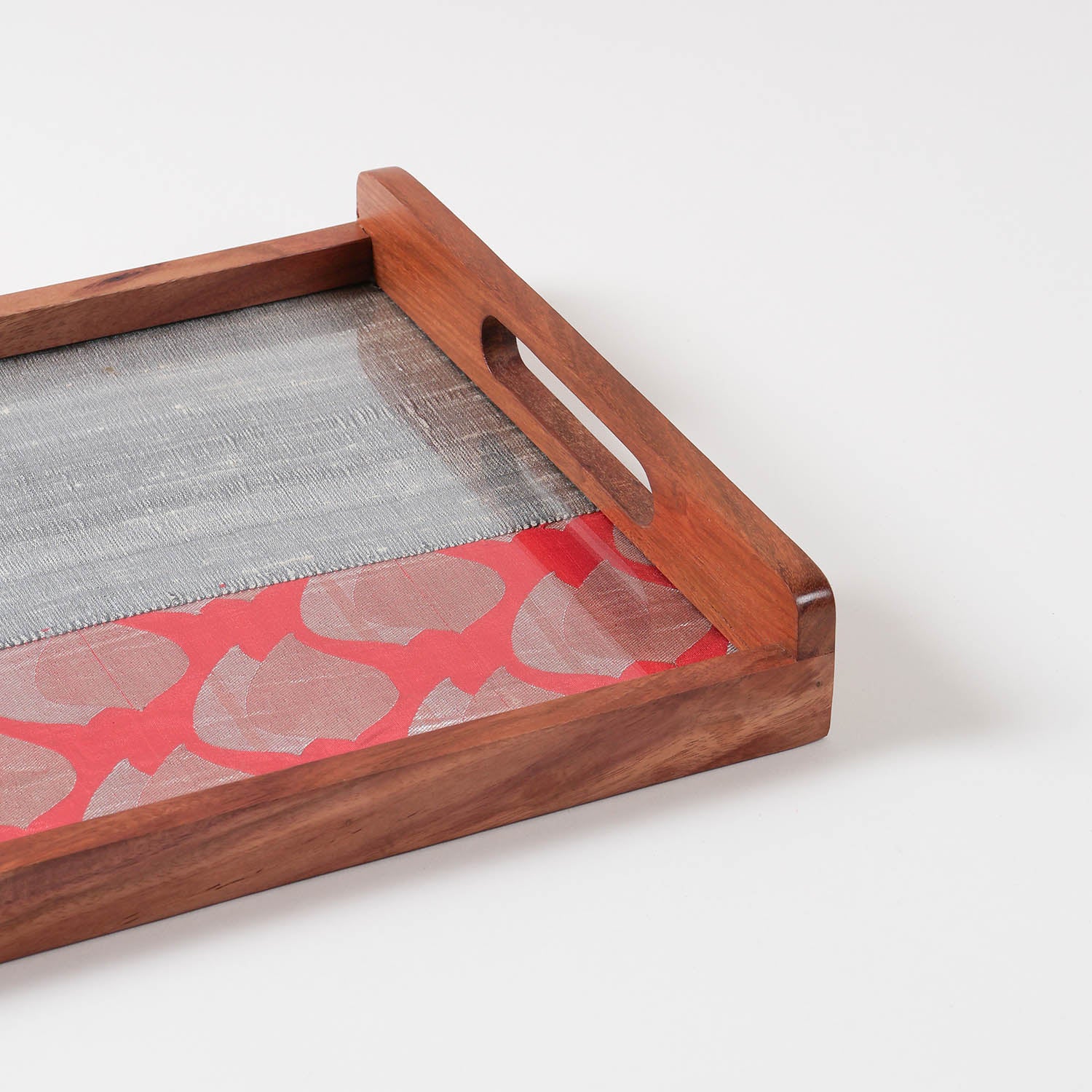 Angled close-up of red and grey chanderi fabric with golden paisley motifs used in a handcrafted wooden serving tray