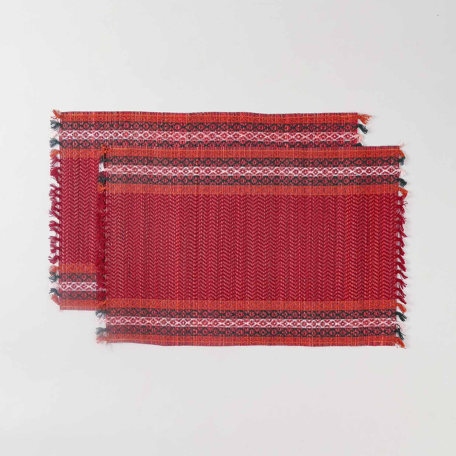 Set of 2 red Madhurkathi placemats displayed flat, showcasing handwoven river grass texture and green, white, and orange borders